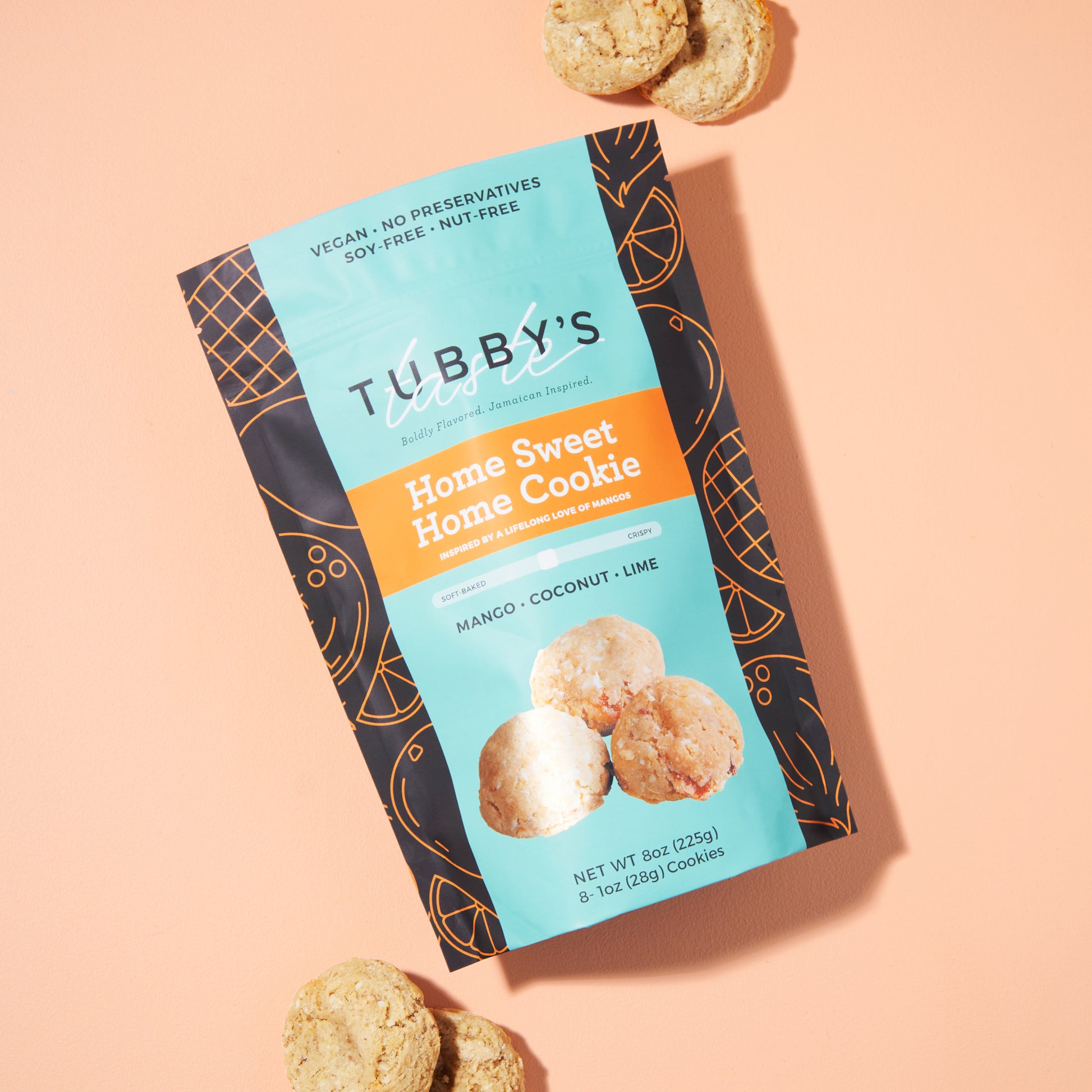 Four Mango Coconut Lime cookies coming out of a Tubby's Taste bag labeled Home Sweet Home on a salmon colored background.