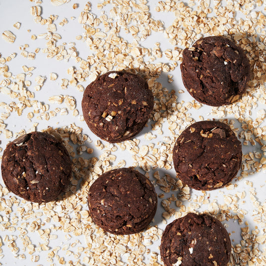 Mocha Oat Chocolate Chip Cookies on a white background with oats sprinkled around them