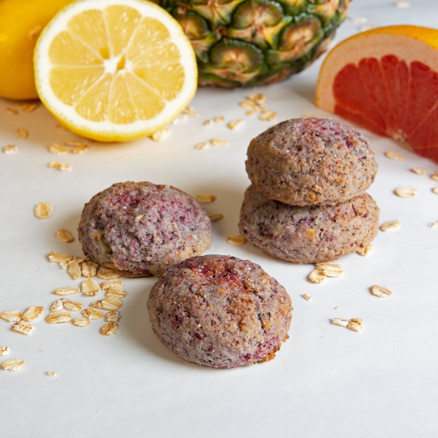 4 Grapefruit Pineapple hibiscus cookies on a white background with a cut up grapefruit, lemon, and pineapple in the background.