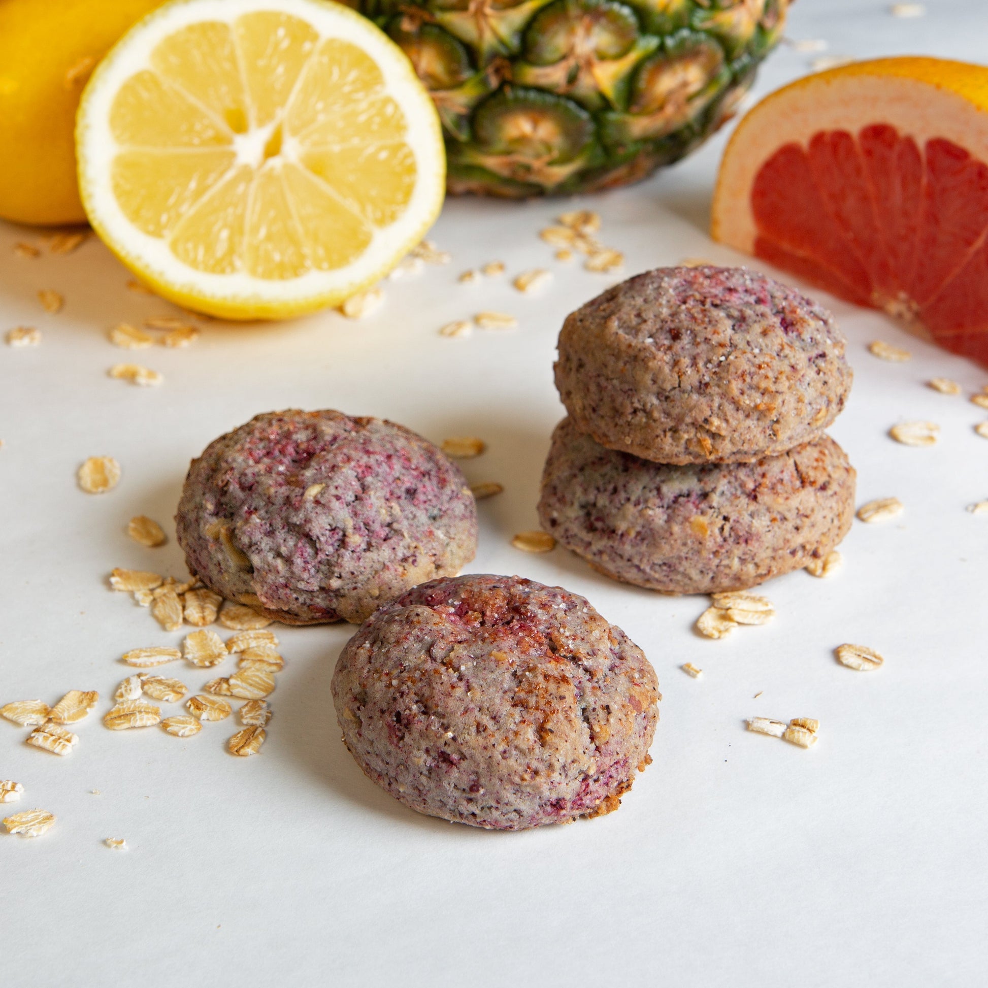 4 Grapefruit Pineapple hibiscus cookies on a white background with a cut up grapefruit, lemon, and pineapple in the background.